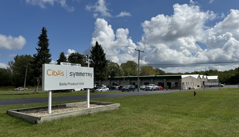 Company sign in grass in front of production building